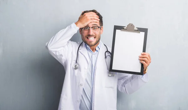 Bonito Jovem Médico Homem Sobre Parede Grunge Cinza Segurando Prancheta — Fotografia de Stock