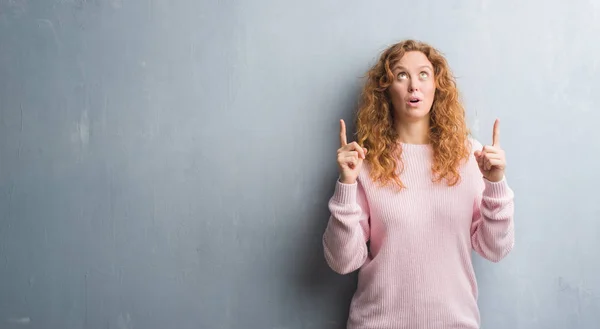 Jonge Roodharige Vrouw Grijs Grunge Muur Dragen Roze Trui Verbaasd — Stockfoto