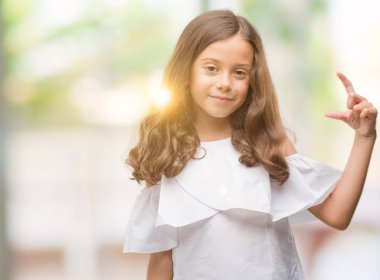 Esmer Latin kız gülümseyerek ve süre seyir ve kamera boyutu işaret parmaklarıyla yapıyor el ile kendine güvenen el hareketi. Ölçü kavramı.