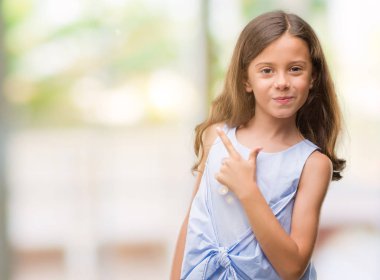 Esmer Latin kız neşeli bir gülümseme ile el ve parmak kadar kameraya bakarak yüzündeki mutlu ve doğal ifade ile yan ile işaret eden yüz.