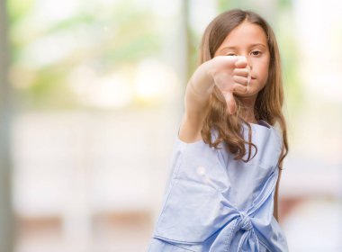 Mutsuz ve kızgın ret gösterilen ve başparmak aşağı hareketi ile negatif seyir esmer Latin kız. Kötü ifade.