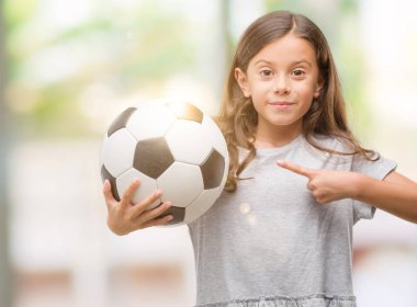 Esmer Latin kız futbol futbol topu çok mutlu el ve parmak ile işaret tutan