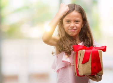 Esmer Latin kız bir hediye tutarak rahatsız ve boşa çıkarmak ile öfke, çılgın da yükseltilmiş el ile bağırmaya kavramı öfke