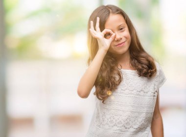 Esmer Latin kız gülümsüyor, parmakları ile mutlu yüz üzerinden seyir göz el ile ok jest yapıyor.