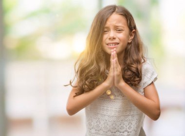 Esmer İspanyol kız yalvarıyor ve umut ifade yüzünde çok duygusal ve endişe ile birlikte elleriyle dua. Bağışlanmak. Din kavramı.