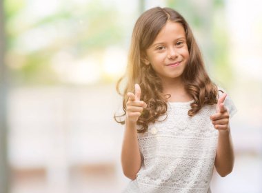 Esmer İspanyol kız kameraya mutlu ve komik suratla parmakları işaret. İyi enerji ve vibes.