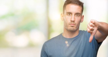 Mutsuz ve kızgın ret gösterilen ve başparmak aşağı hareketi ile negatif seyir yakışıklı genç casual adam. Kötü ifade.