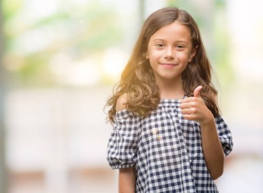 Esmer Latin kız ok işareti, başparmak ile parmak, mükemmel işareti yapıyor kocaman bir gülümseme ile siyah beyaz elbise mutlu var