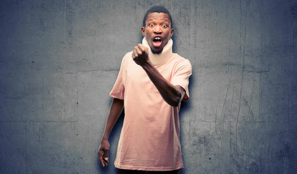 Injured african black man wearing neck brace irritated and angry expressing negative emotion, annoyed with someone