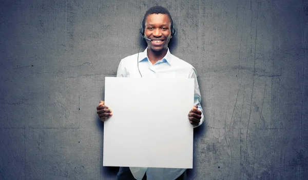 Black man consultant of call center holding blank advertising banner, good poster for ad, offer or announcement, big paper billboard