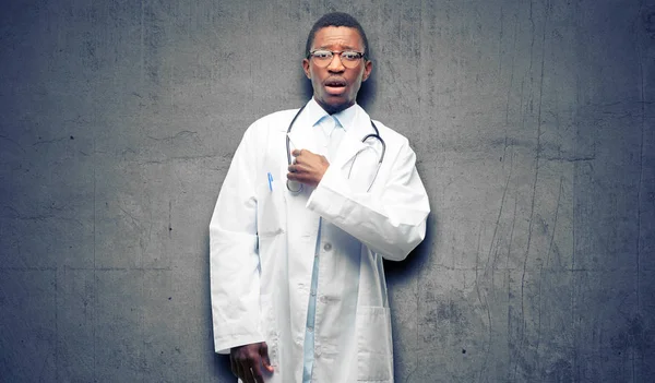 Young black doctor, medical professional happy and surprised cheering expressing wow gesture, pointing with finger