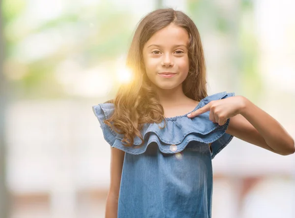 Brünettes Hispanisches Mädchen Trägt Jeanskleid Mit Überraschungsgesicht Und Zeigt Mit — Stockfoto