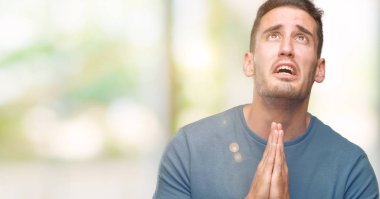 Yalvarıyor ve umut ifade yüzünde çok duygusal ve endişe ile birlikte elleriyle dua rahat yakışıklı genç. Bağışlanmak. Din kavramı.