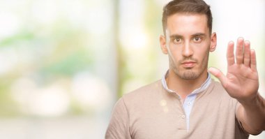 Yakışıklı genç adam açık eliyle dur işareti ile ciddi ve kendine güvenen ifade, savunma hareketi yapıyor