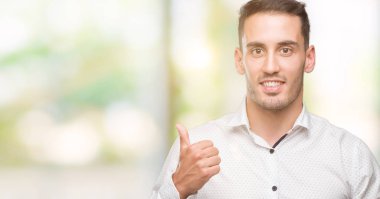 Yakışıklı genç iş adamı ok işareti, başparmak ile parmak, mükemmel işareti yapıyor kocaman bir gülümseme ile mutlu