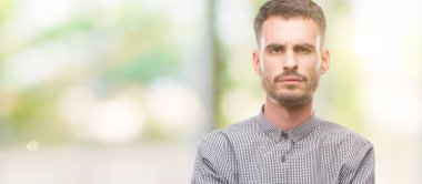 Genç hipster adam şüpheci ve sinir, onaylamayan ifade yüz çapraz kolları üzerinde. Negatif kişi.