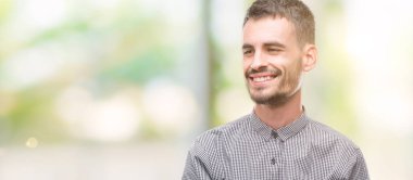 Uzak tarafına yüzünde, doğal ifade gülümseme ile görünen genç hipster adam. Kendine güvenen gülüyor.