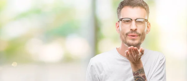 Joven Hombre Adulto Tatuado Mirando Cámara Soplando Beso Con Mano —  Fotos de Stock