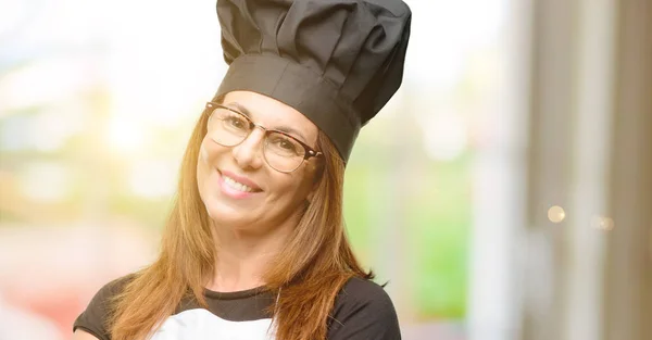 中年厨师妇女穿着厨师围裙与交叉双臂自信和快乐的大自然笑笑 — 图库照片
