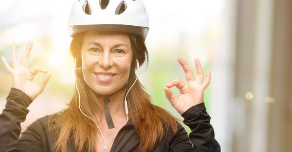 中年骑自行车的妇女使用耳机做 标志手势双手表示冥想和放松 — 图库照片