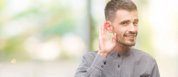 Hipster Młody Człowiek Uśmiechający Się Ręką Nad Uchem Słucha Rozprawy — Zdjęcie stockowe