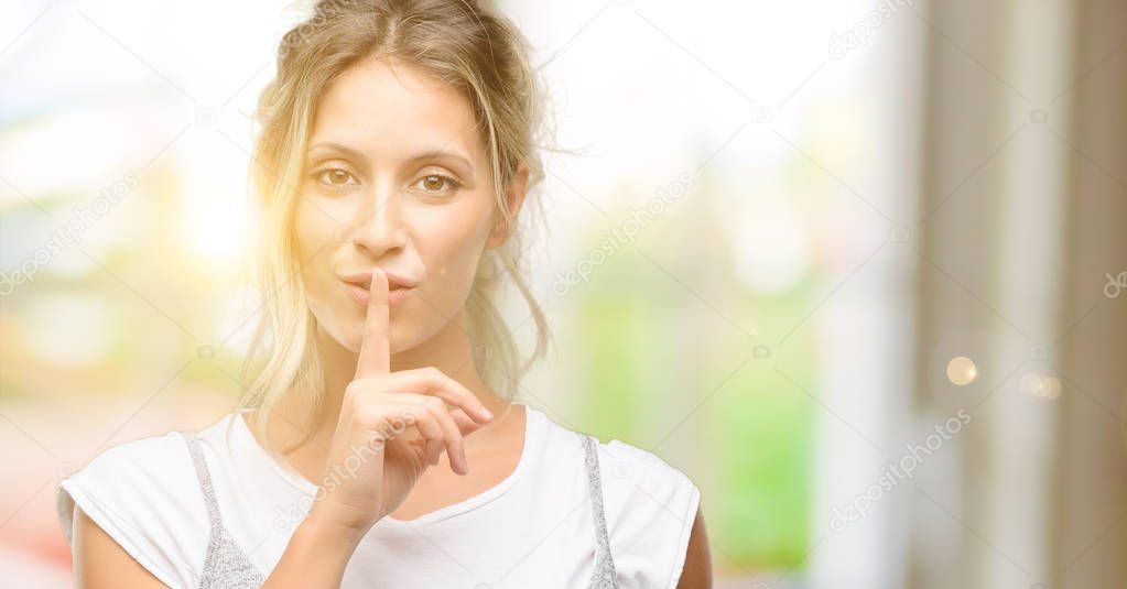 Young beautiful woman with index finger on lips, ask to be quiet. Silence and secret concept