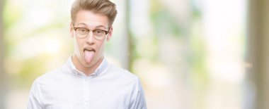 Genç yakışıklı sarışın adam dilini out komik ifade ile mutlu. Duygu kavramı.