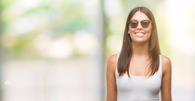 Genç güzel İspanyol yüzünde mutlu ve güzel bir gülümseme ile güneş gözlüğü takıyor. Şanslı kişi.