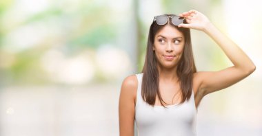 Genç güzel İspanyol görünümlü yan ve dik dik bakma uzağa düşünce gülümseyen güneş gözlüğü takıyor.