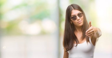 Genç güzel İspanyol tebrik ve konuksever dost sunan karşılıklı gülümseyen güneş gözlüğü takıyor. Başarılı iş.