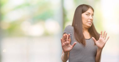 Şokta bağırarak genç güzel İspanyol kadın korkuyor ve korku ifade dur hareketi el ile ile çok korkmuş. Panik kavramı.