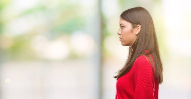 Kırmızı kazaklı tarafına, seyir giyen genç güzel İspanyol dinlenmek doğal yüz emin gülümseme ile pozuyla profili.