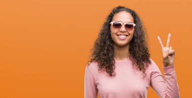 Güzel genç İspanyol kadın ve parmak ikinci ile gülümseyen ise kendinden emin ve mutlu yukarıyı gösteren güneş gözlüğü takıyor.