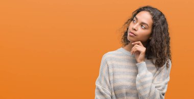 Çene düşünme hakkında soru, dalgın ifade üzerine el ile çizgili süveter giyen güzel genç İspanyol kadın. Düşünceli yüzüyle gülümsüyor. Şüphe kavramı.