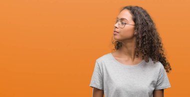 Güzel genç İspanyol kadın görünümlü yan ve dik dik bakma uzağa düşünce gülümseyen gözlüklü.