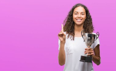 Kupa sürpriz bir fikir ya da soru işaret parmağı ile gülen yüz, bir numara tutan genç İspanyol kadın