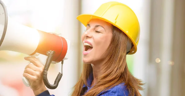 Engineer construction worker woman communicates shouting loud holding a megaphone, expressing success and positive concept, idea for marketing or sales