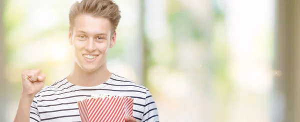 Young Handsome Blond Man Eating Popcorn Screaming Proud Celebrating Victory — Stock Photo, Image