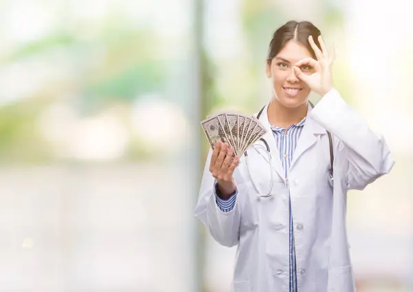 Jovem Hispânico Médico Mulher Segurando Dólares Com Rosto Feliz Sorrindo — Fotografia de Stock