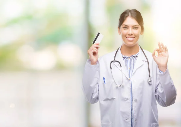 Joven Doctora Hispana Sosteniendo Tarjeta Crédito Haciendo Signo Con Los —  Fotos de Stock