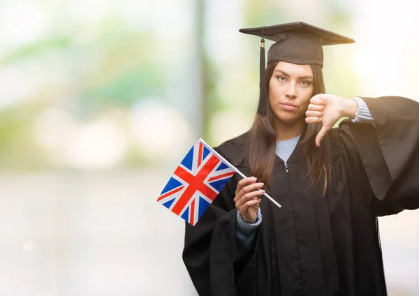 年轻的西班牙裔女子身穿制服的英国国旗与愤怒的脸 否定的标志显示不喜欢拇指向下 拒绝概念 — 图库照片