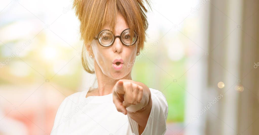 Crazy middle age woman wearing silly glasses pointing to the front with finger