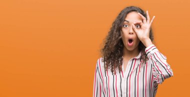 Güzel genç İspanyol kadının iyi bir jest yapması sürpriz yüz, göz parmaklarının arasından seyir ile şok. İmansız ifade.