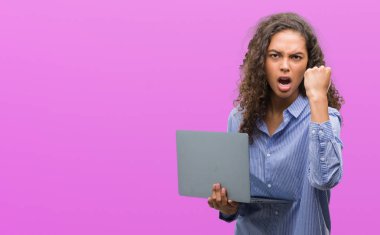 Bilgisayar dizüstü tutan genç İspanyol kadın rahatsız ve boşa çıkarmak ile öfke, çılgın da yükseltilmiş el ile bağırmaya kavramı öfke