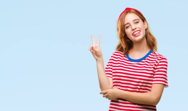 Genç güzel kadın mutlu yüz zafer işareti yaparken kameraya göz kırpıyor ile gülümseyen izole arka plan yüzünden. İki numaralı.