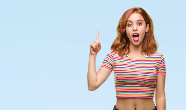 Genç güzel kadın başarılı fikirle parmağı yukarıyı izole arka plan yüzünden. Çıktıktan ve mutlu. Bir numara.