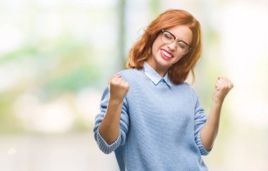 Gülümseyen ve başarı için çığlık genç güzel kadın izole arka plan çok mutlu ve heyecanlı kaldırdı, silah ile kazanan jest yapıyor kış kazak giyiyor. Kutlama kavramı.