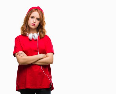 İzole arka yüz çapraz kolları üzerinde kulaklık ve kap şüpheci ve sinir, onaylamayan ifade giyen genç güzel hipster kadın. Negatif kişi.