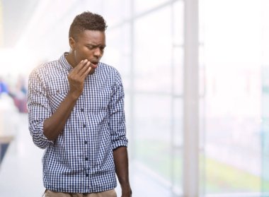 Diş ağrısı veya dişlerde dişlerle ilgili hastalık nedeniyle ağız acı ifadesi ile el ile dokunmak mavi gömlek giymiş genç Afro-Amerikan adam. Diş hekimi kavramı.