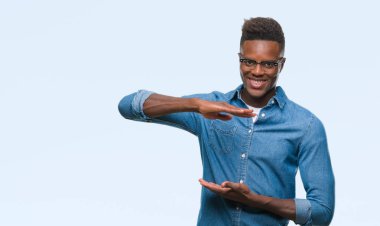 Afrikalı-Amerikalı genç izole arka plan ile büyük ve büyük boy işaret, ölçü birimi sembol gösteren el eller üzerinde. Kameraya bakarak gülümsüyordu. Ölçüm kavramı.